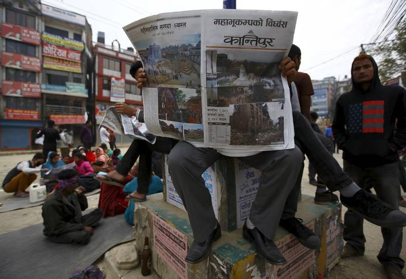Folk i Katmandu er ute på gatene og noen leser avisen dagen etter det store jordskjelvet. Etterskjelvene får mange til holde seg ute av husene.
