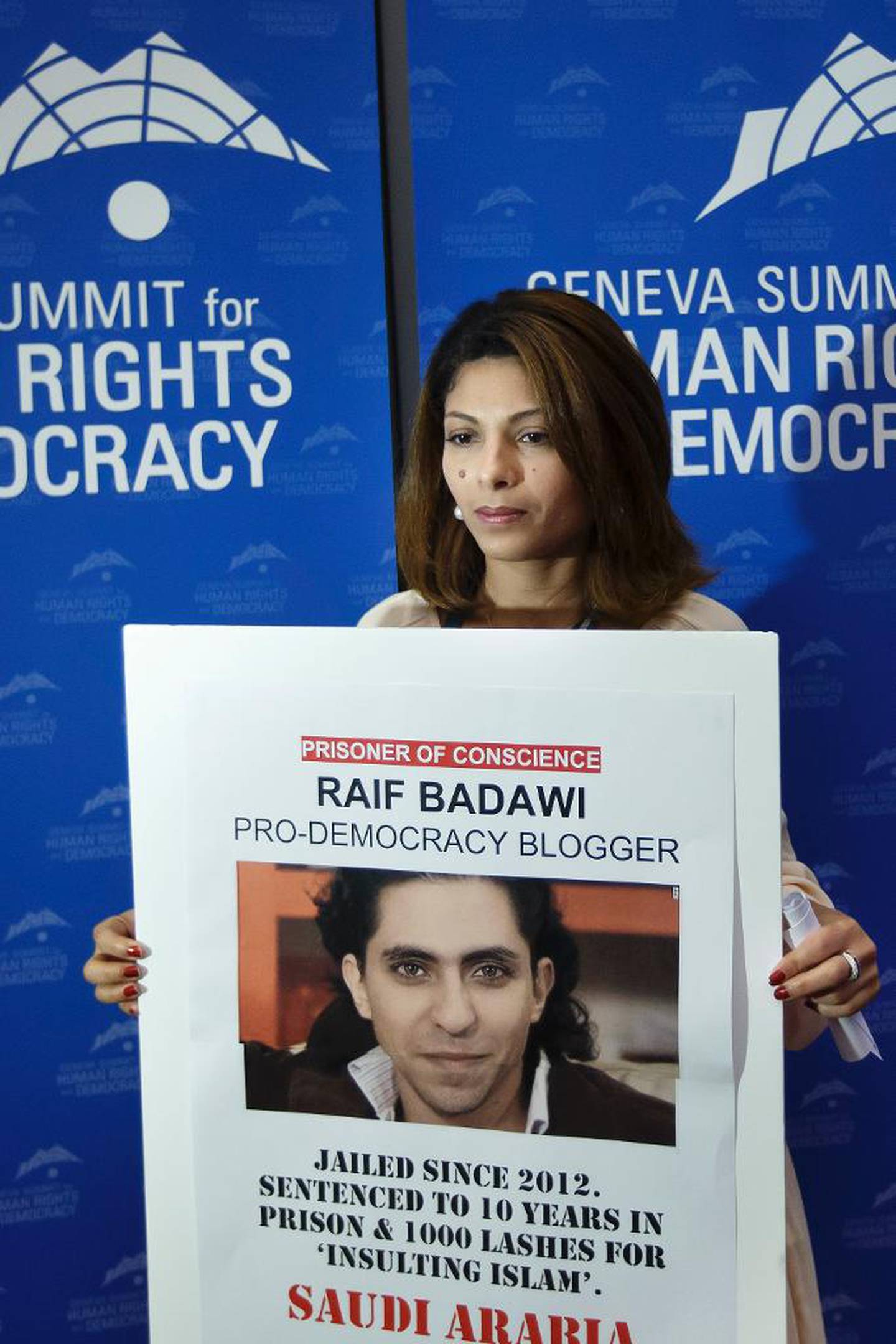 Den saudiske bloggeren Raid Badawis kone Ensaf Haider holder opp et bilde av mannen sin under et toppmøte for menneskerettigheter og demokrati i Geneve i februar i år.