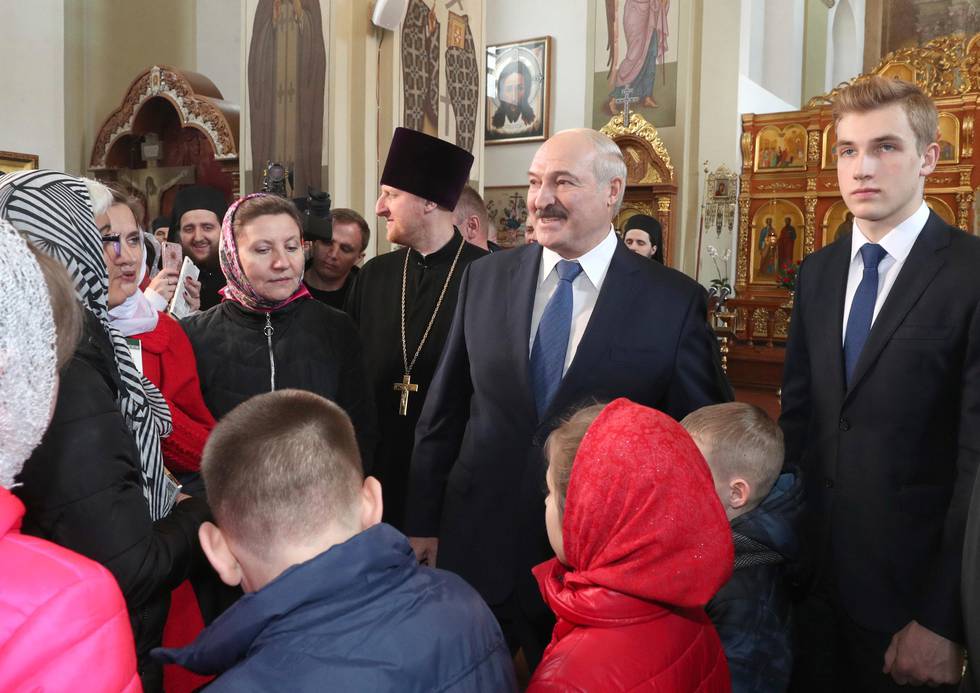 In this photo taken Sunday, April 19, 2020, Belarusian President Alexander Lukashenko, centre, with his son Nikolai, right, talks with believers during the Orthodox Easter service at a church in the village of Malye Lyady outskirts Minsk, Belarus. Schools reopened Monday in Belarus following an extended spring break, but authorities allowed parents to keep their children at home even though the country specifically steered clear of closures and restrictions on public movement during the coronavirus pandemic. (Nikolai Petrov/Pool Photo via AP)