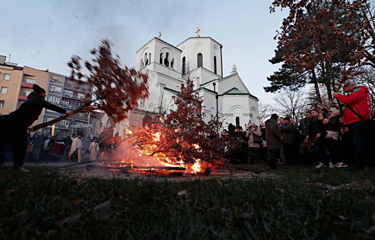A man burns dried oak branches, the Yule log symbol for the Orthodox Christmas Eve, in front of St. Sava church in Belgrade, Serbia, Jan. 6, 2020. Orthodox believers in Serbia celebrate Christmas on January 7, according to the Julian calendar. (AP Photo/Darko Vojinovic)