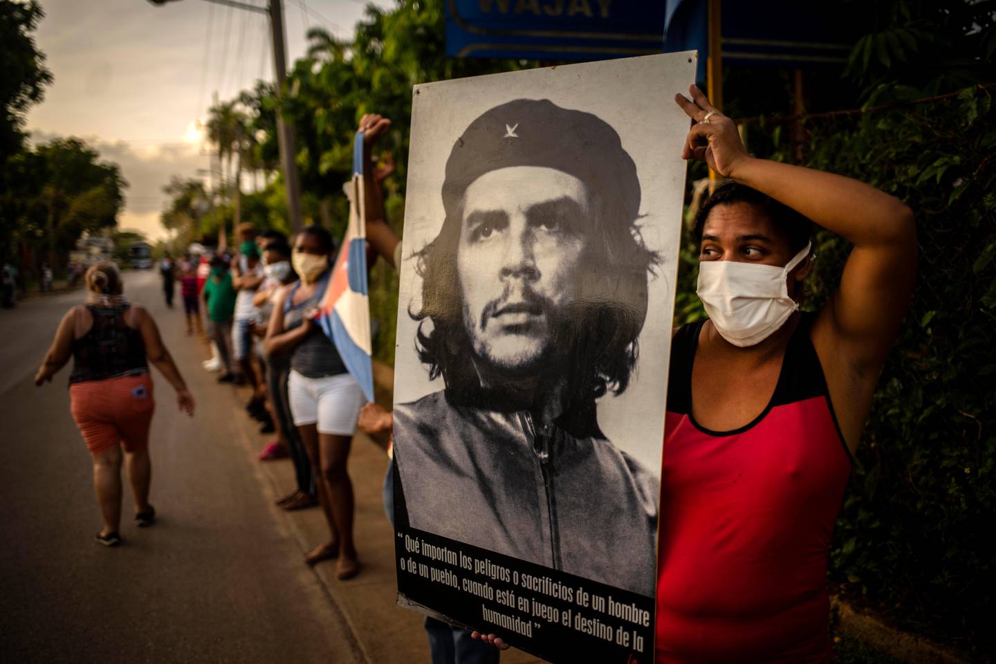 A woman holds an image of Ernesto "Che" Guevara while awaiting the arrival of the first Cuban medical brigade of the Henry Reeve Contingent in Havana, Cuba, June 8, 2020. The Cuban doctors had gone to Italy on March 22 to help during the COVID -19 emergency in the Lombardy region. (AP Photo/Ramon Espinosa)