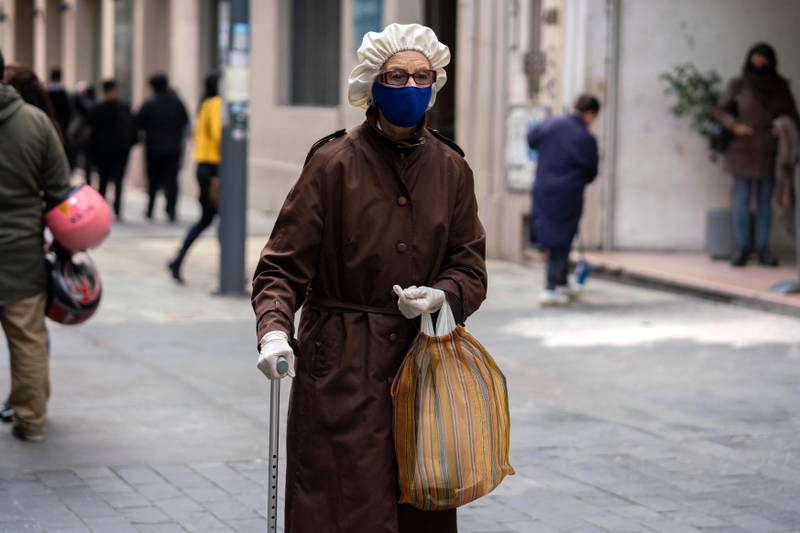 An elderly woman wearing a protective face mask and disposable gloves as a precaution against the spread of new coronavirus, walks in downtown Montevideo, Uruguay, Friday, May 15, 2020. (AP Photo/Matilde Campodonico)