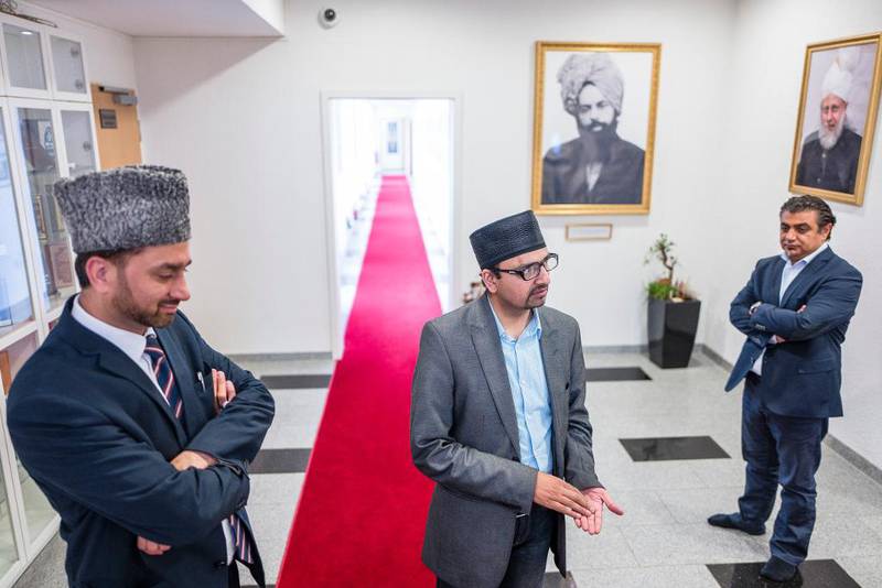 Imam Shahid Mahmood Kahloon (t.v.), moskéleder Zahoor Ahmad Ch, og presseansvarlig Fazal Anas står foran bildene av grunn­legger Mirza Ghulam Ahmad og øverste åndelige leder, kalif Mirza Masroor Ahmad.