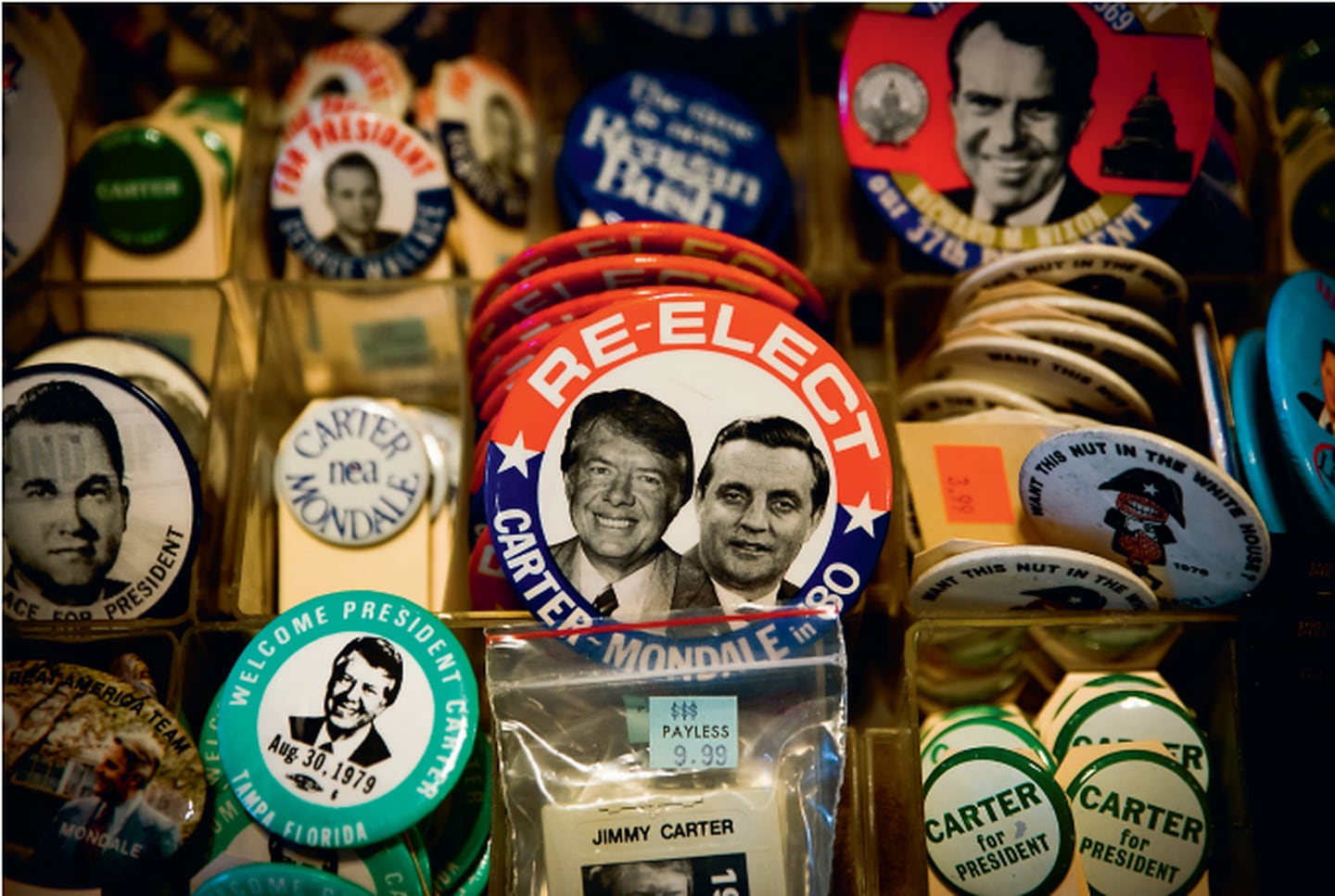«Gjenvelg Carter og Mondale»: Et ekko av presidentvalgkampen i 1980 er blant tusenvis av samleobjekter til salgs i souvenirbutikkene i Plains. Skandaleombruste Richard Nixon spøker i bakgrunnen (t.h).