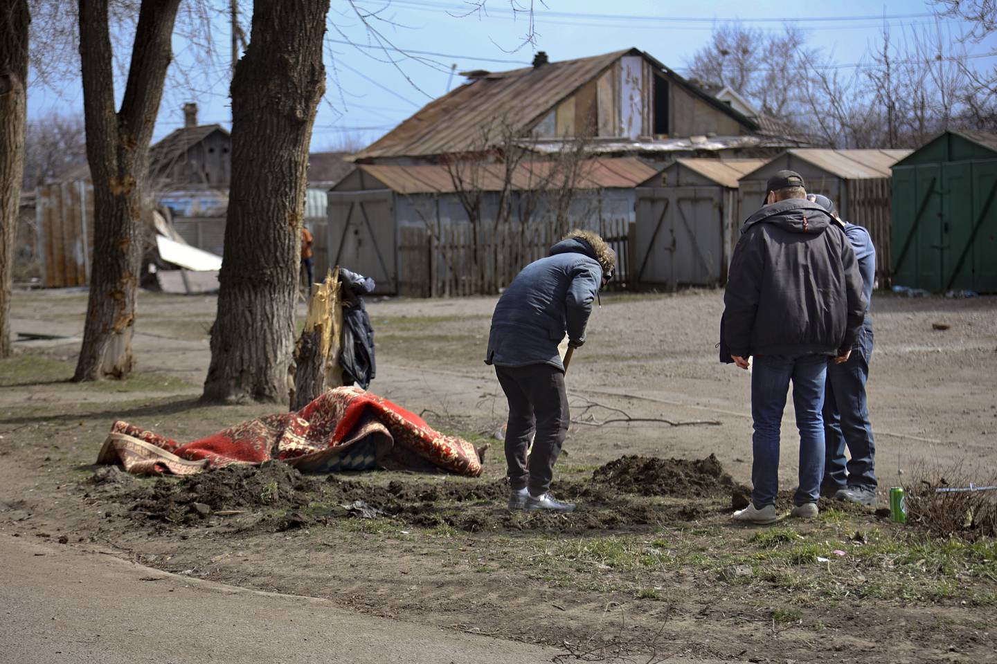 A man digs a grave to bury the body of a victim from fighting on the outskirts of Mariupol, Ukraine, in territory under control of the separatist government of the Donetsk People's Republic, on Tuesday, March 29, 2022. (AP Photo/Alexei Alexandrov)
