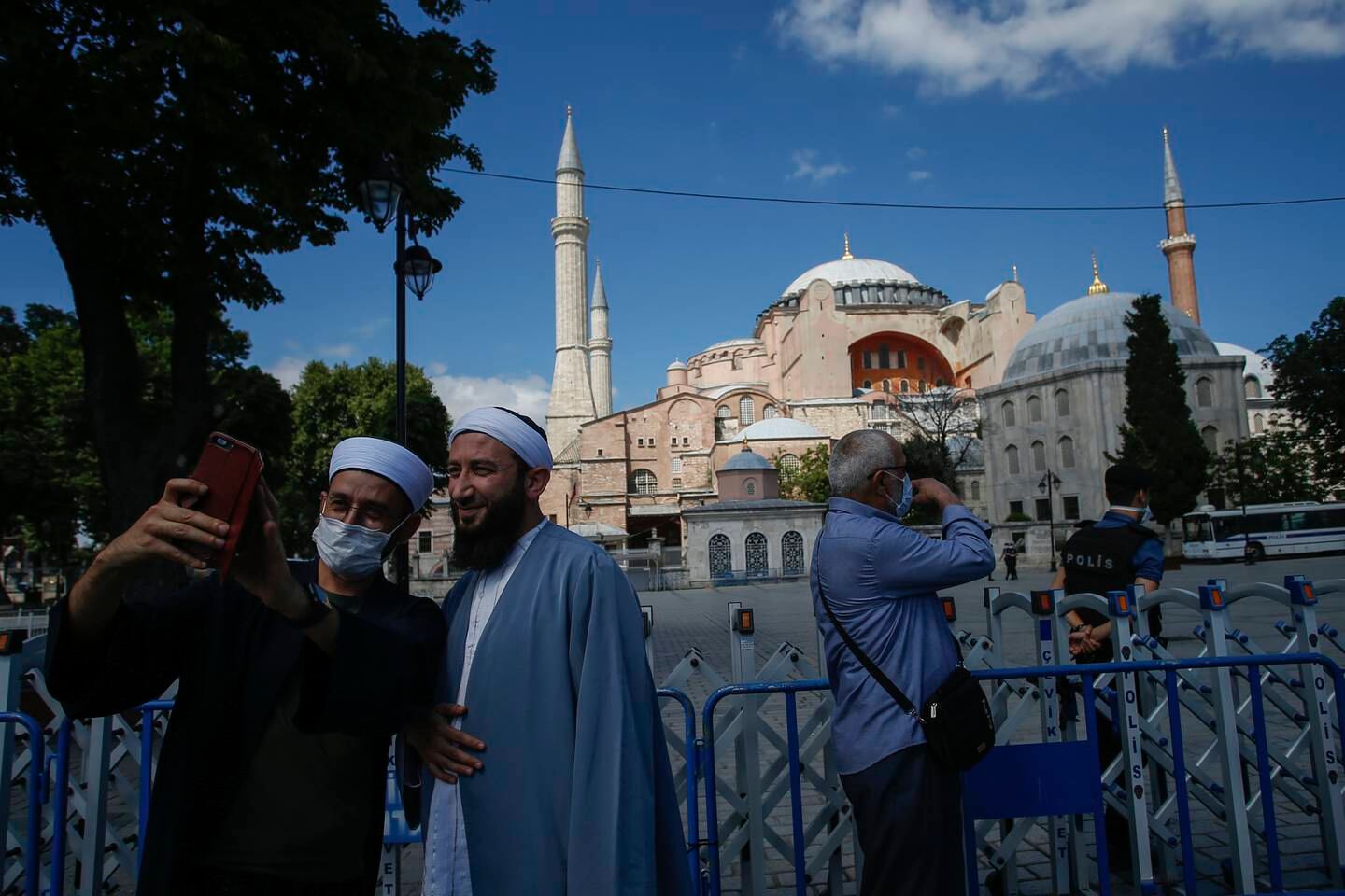 People use their mobile to take a selfie picture outside the now closed Byzantine-era Hagia Sophia, one of Istanbul's main tourist attractions in the historic Sultanahmet district of Istanbul, Saturday, July 11, 2020. Turkey's President Recep Tayyip Erdogan formally reconverted Hagia Sophia into a mosque and declared it open for Muslim worship, hours after a high court annulled a 1934 decision that had made the religious landmark a museum.The decision sparked deep dismay among Orthodox Christians. Originally a cathedral, Hagia Sophia was turned into a mosque after Istanbul's conquest by the Ottoman Empire but had been a museum for the last 86 years, drawing millions of tourists annually. (AP Photo/Emrah Gurel)