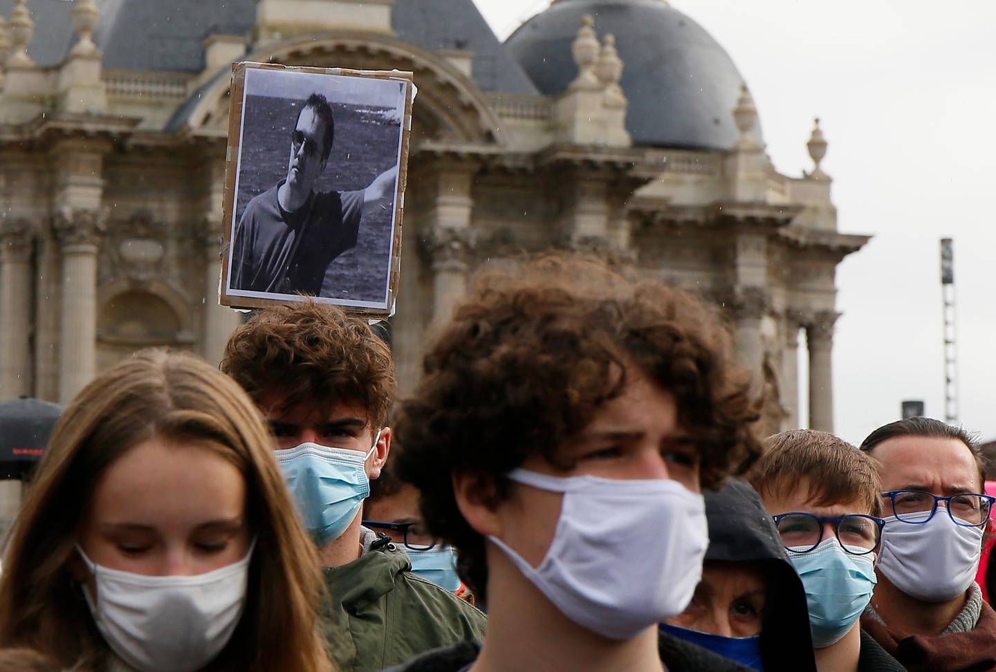 A portrait of Samuel Paty is held up as people gather on Republique square in Lille, northern France, Sunday Oct. 18, 2020. Demonstrators in France on Sunday took part in gatherings in support of freedom of speech and in tribute to a history teacher who was beheaded near Paris after discussing caricatures of Islams Prophet Muhammad with his class. (AP Photo/Michel Spingler)