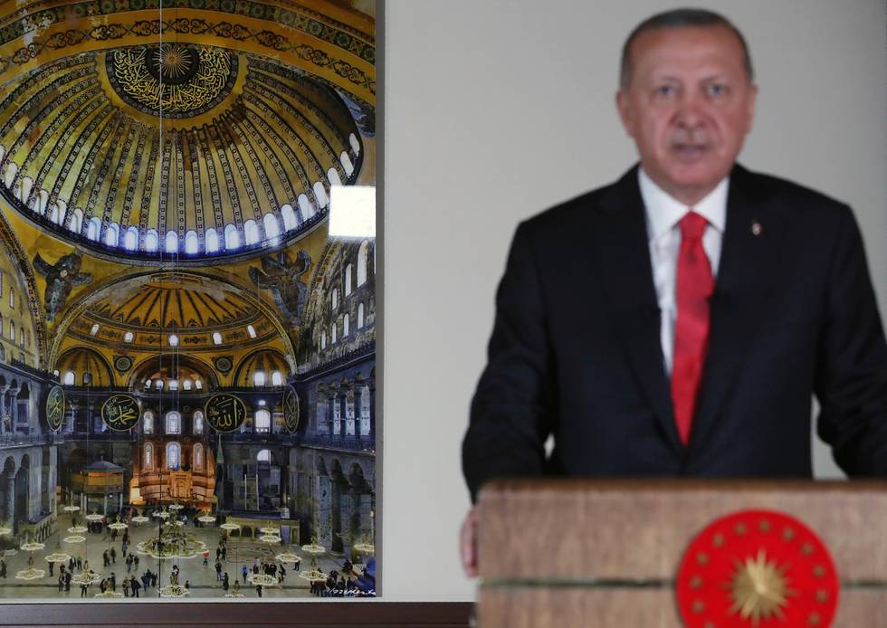 Turkey's President Recep Tayyip Erdogan, backdropped by a photograph of the Byzantine-era Hagia Sophia, one of Istanbul's main tourist attractions, delivers a televised address to the nation, in Ankara, Turkey, Friday, July 10, 2020. Erdogan formally reconverted Hagia Sophia into a mosque and declared it open for Muslim worship, hours after Turkey's highest administrative court annulled a 1934 decision that had made the religious landmark a museum. (Presidential Press Service via AP, Pool)