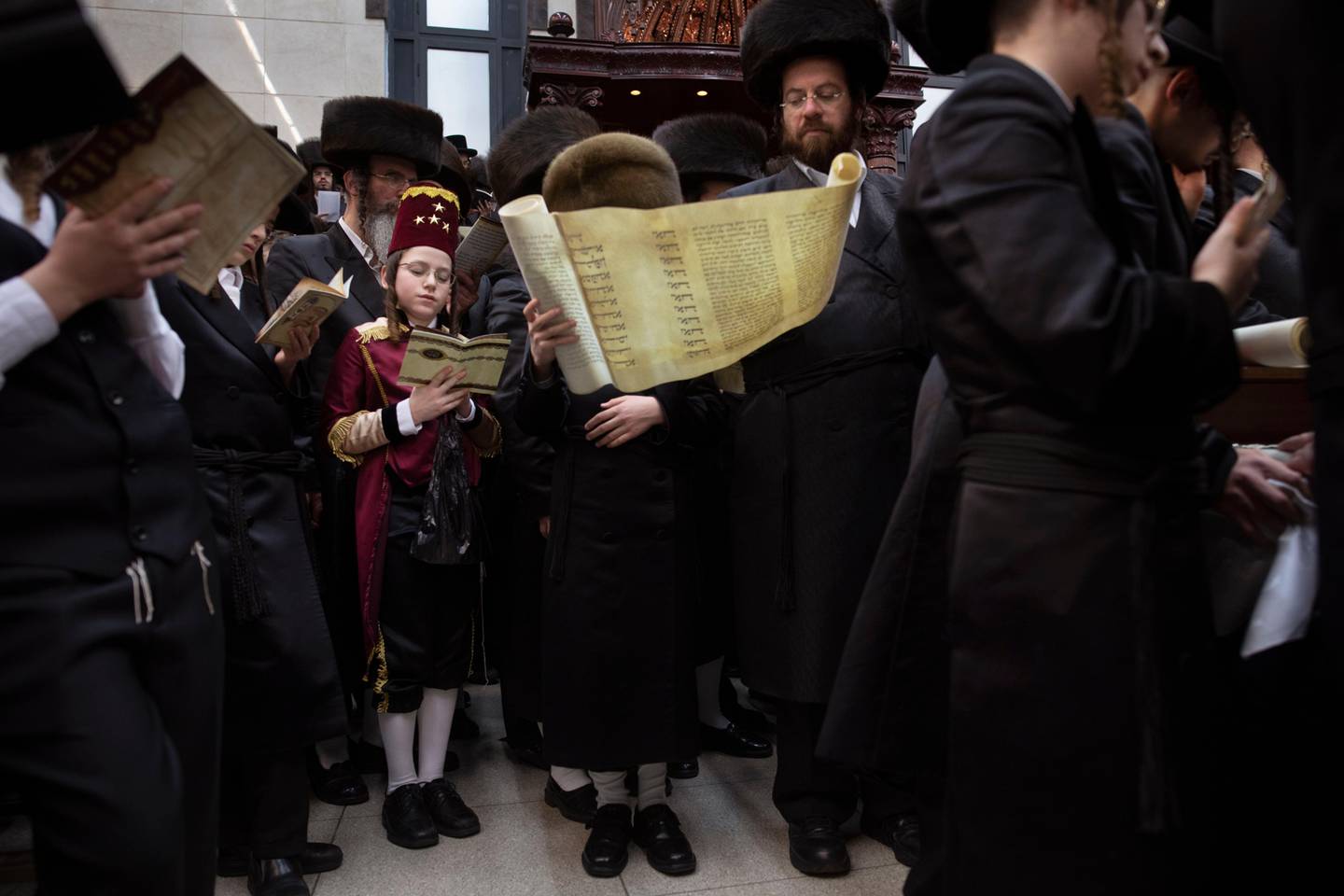 Jewish Ultra-Orthodox men and children, some wearing costumes, read the Book of Esther which tells the story of the Jewish festival of Purim, at a synagogue in Bnei Brak, Israel, Monday, March 9, 2020. The holiday commemorates the Jews' salvation from genocide in ancient Persia, as recounted in the Book of Esther. (AP Photo/Oded Balilty)