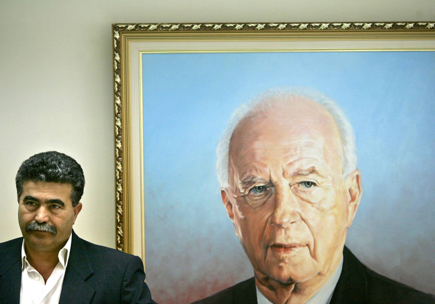 Israeli Labor Party leader Amir Peretz stands in front of a painting showing the late Prime Minister and Labor leader Yitzhak Rabin, during the weekly meeting at the Knesset in Jerusalem, Monday, Dec. 12, 2005. According to the latest polls, the Labor Party would take 23 seats of 120 seats in parliament in the upcoming March elections, Ariel Sharon's new Kadima Party would capture 39, and Likud, the hard-line party that Ariel Sharon recently quit, 13. Amir Peretz is campaigning on a platform of social and economic issues and is perceived as being inexperienced with security matters. (AP Photo/Kevin Frayer)