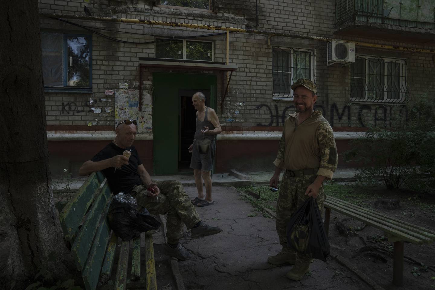 Soldater hviler og tar seg en is foran boligblokka der Valerij Iltsjenko bor. Foto: Nariman El-Mofty / AP / NTB
