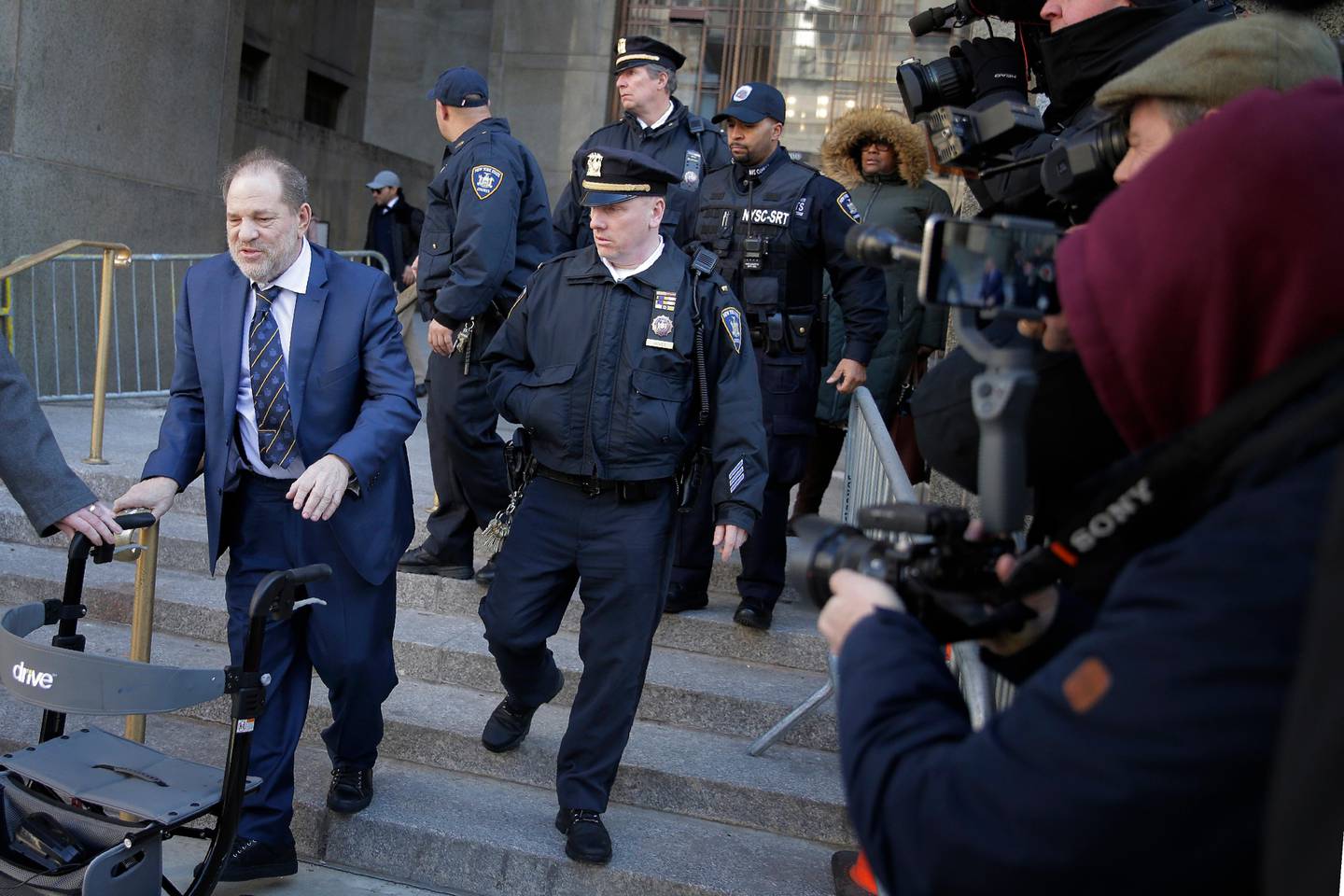 Harvey Weinstein, left, leaves a Manhattan courthouse after closing arguments in his rape trial in New York, Friday, Feb. 14, 2020. (AP Photo/Seth Wenig)