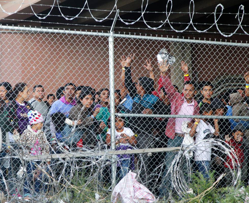 FILE - In this March 27, 2019, file photo, Central American migrants wait for food in a pen erected by U.S. Customs and Border Protection to process a surge of migrant families and unaccompanied minors in El Paso, Texas. Texas Gov. Greg Abbott says he's sending another 1,000 National Guard troops to the U.S.-Mexico border and blasted Congress as a "group of reprobates" over the growing humanitarian crisis. Abbott said Friday, June 21, 2019, that the additional Guard members will assist at detention facilities and at ports of entry. . (AP Photo/Cedar Attanasio, File)