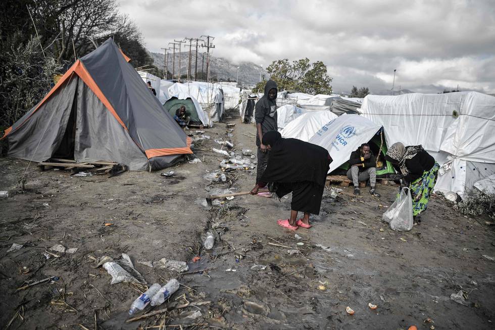 A group of women try to clean the paths in between the tents in the makeshift part of the Vial refugee camp, on the Greek island of Chios, on December 11, 2019. - The Vial camp on the island of Chios has only 1,000 places, but nearly 5,000 asylum seekers currently live there in unsanitary conditions and many camps  situated in the nearby olive groove are without toilets, bathrooms, electricity and water. In addition to lack of hygiene, "insecurity, especially at night, is often mentioned by women," reports the Office of the High Commissioner for Refugees (UNHCR). In the improvised camp, single men of various nationalities live together, adolescent girls or elderly or pregnant women. The NGO Human Rights Watch recently sounded the alarm, calling on the Greek government to "act immediately to ensure safe and humane conditions for women and girls" in camps on the Greek islands. (Photo by LOUISA GOULIAMAKI / AFP)