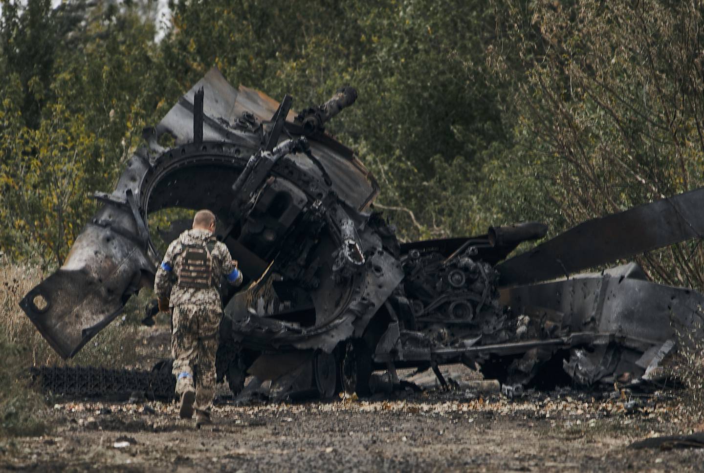 En ukrainsk soldat ved en ødelagt russisk stridsvogn ved veien til Balaklija i Kharkiv-regionen søndag. Foto: AP / NTB
