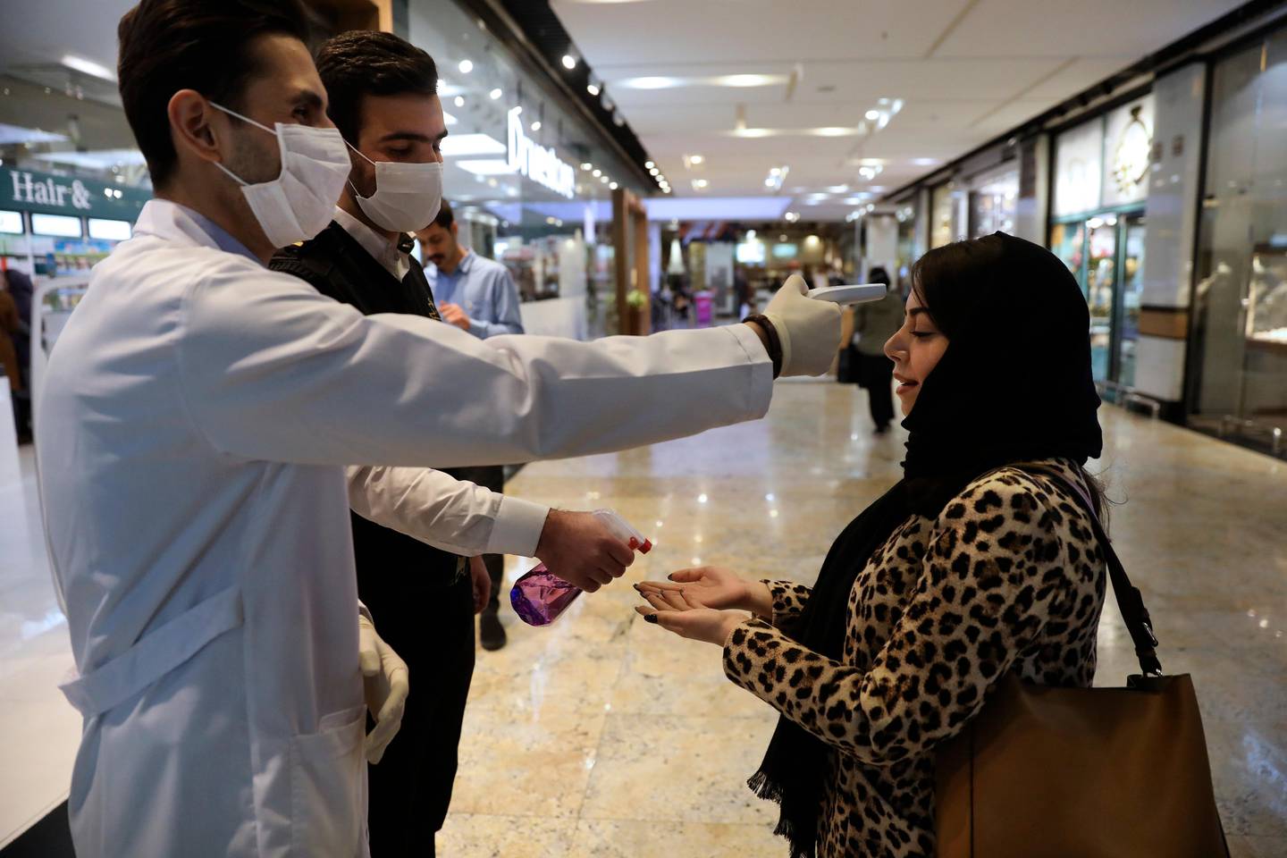 A woman has her temperature checked and her hands disinfected as she enters the Palladium Shopping Center, in northern Tehran, Iran, Tuesday, March 3, 2020. Iran's supreme leader put the Islamic Republic's armed forces on alert Tuesday to assist health officials in combating the outbreak of the new coronavirus, the deadliest outside of China. (AP Photo/Vahid Salemi)