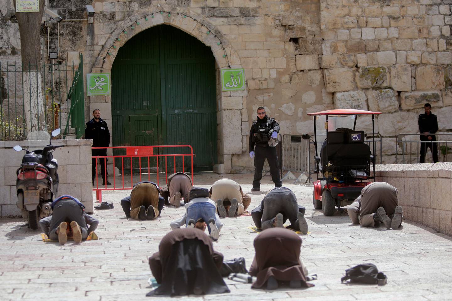 People pray in front of the shuttered gates to al-Aqsa mosque compound as all prayers are suspended to prevent the spread of coronavirus in Jerusalem, Monday, March 23, 2020. In Israel daily life has largely shut down with coronavirus cases multiplying greatly over the past week, (AP Photo/Mahmoud Illean)