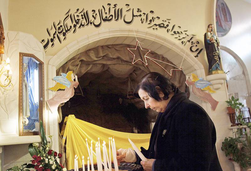 A Palestinian Christian woman lights candles during a mass at the Latin Church of Visitation in the village of Al-Zababdeh near the West Bank town of Jenin, Sunday, Dec. 18. 2011. (AP  Photo/Mohammed Ballas)