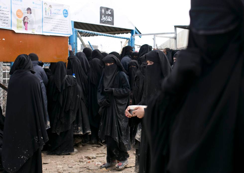 In this Sunday, March 31, 2019, photo, women line up for aid supplies at Al-Hol camp in Hassakeh province, Syria. The camp is past full capacity, with more than 70,000 residents from former Islamic State-held areas in Syria. (AP Photo/Maya Alleruzzo)