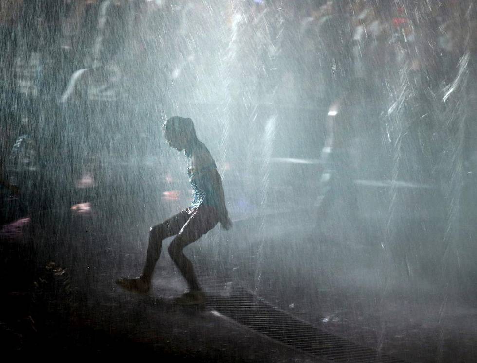 En jente kjøler seg ned i fontenevann på en varm junikveld i Jianli i Hubei-provinsen. Kina er blant landene som har økt sine klimautslipp ­dramatisk som følge av globalisert handel.