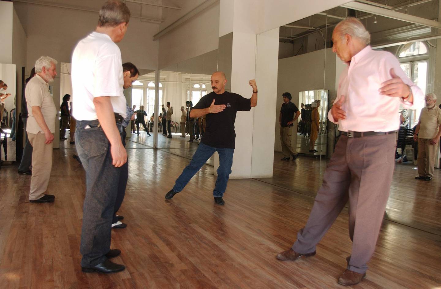 Tango instructor Jorge Firpo, center, shows students Jorge, right, and Irek, left,some steps during a class in the Argentine School of Tango in a shopping mall in Buenos Aires, Sept. 26, 2005. (AP Photo/Daniel Luna)