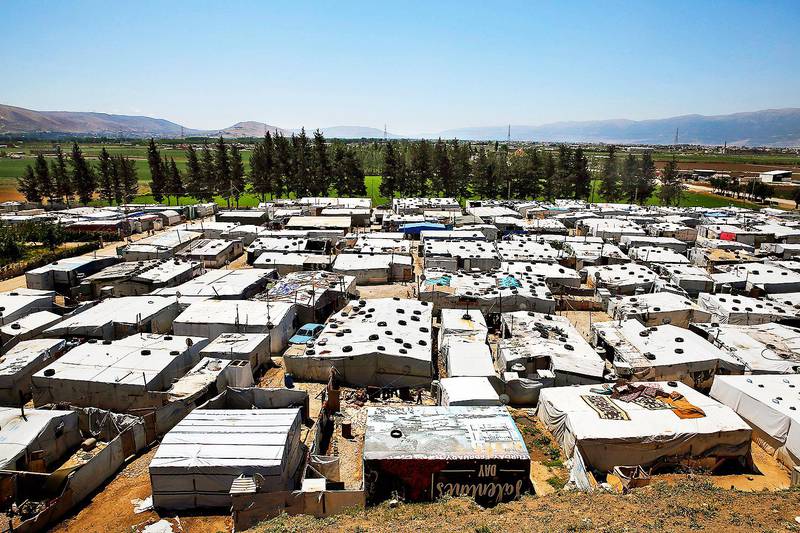 This Monday, April 23, 2018 photo, Syrian refugees walk outside their tents at a Syrian refugee camp in the town of Bar Elias, in Lebanon's Bekaa Valley. A leading international rights group and the U.N.'s refugee agency say Lebanese authorities have been evicting Syrian refugees from towns and camps in Lebanon without any legal basis. (AP Photo/Bilal Hussein)