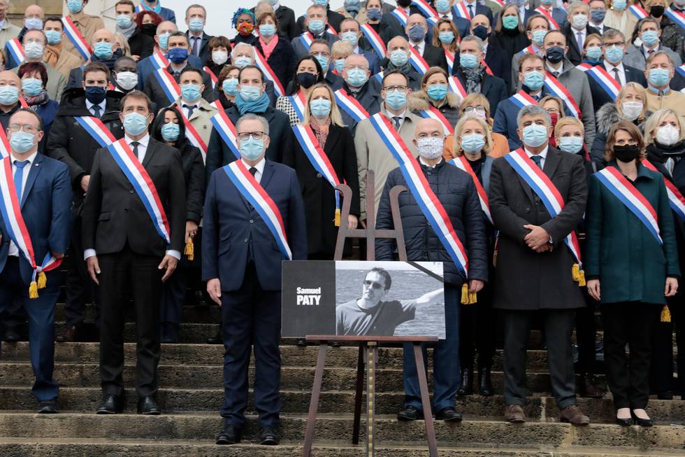 French lawmakers observe a minute silence to pay tribute to slain teacher Samuel Paty, Tuesday, Oct.20, 2020 on the steps of the National Assembly in Paris. A memorial march will be held Tuesday evening near Paris in homage to the history teacher who was beheaded last week, while French police said 16 people remain in custody as part of the investigation into the attack. (AP Photo/Lewis Joly)