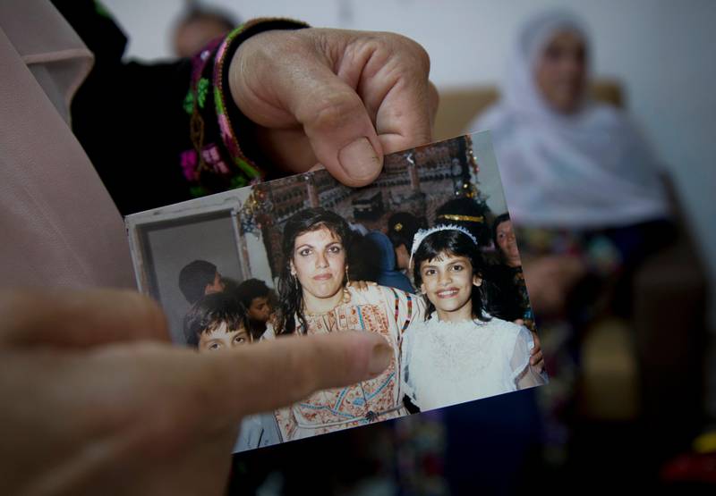 In this Wednesday, Aug. 8, 2018 photo, Fadwa Tlaib, an aunt of Rashida Tlaib points to a young Rashida in a 1987 picture with her mother Fatima and brother Nader, at the family house, in the West Bank village of Beit Ur al-Foqa. The Michigan primary victory of Tlaib, who is expected to become the first Muslim woman and Palestinian-American to serve in the U.S. Congress, is rippling across the Middle East. In the West Bank village where TlaibÄôs mother was born, residents are greeting the news with a mixture of pride and hope that she will take on a U.S. administration widely seen as hostile to the Palestinian cause. (AP Photo/Nasser Nasser)