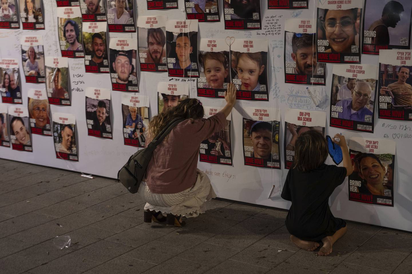 En kvinne holder hånden på bilder av israelere som holdes som gisler på Gazastripen av Hamas. Mer enn 200 holdes fortsatt fanget. Foto: Petros Giannakouris / AP / NTB