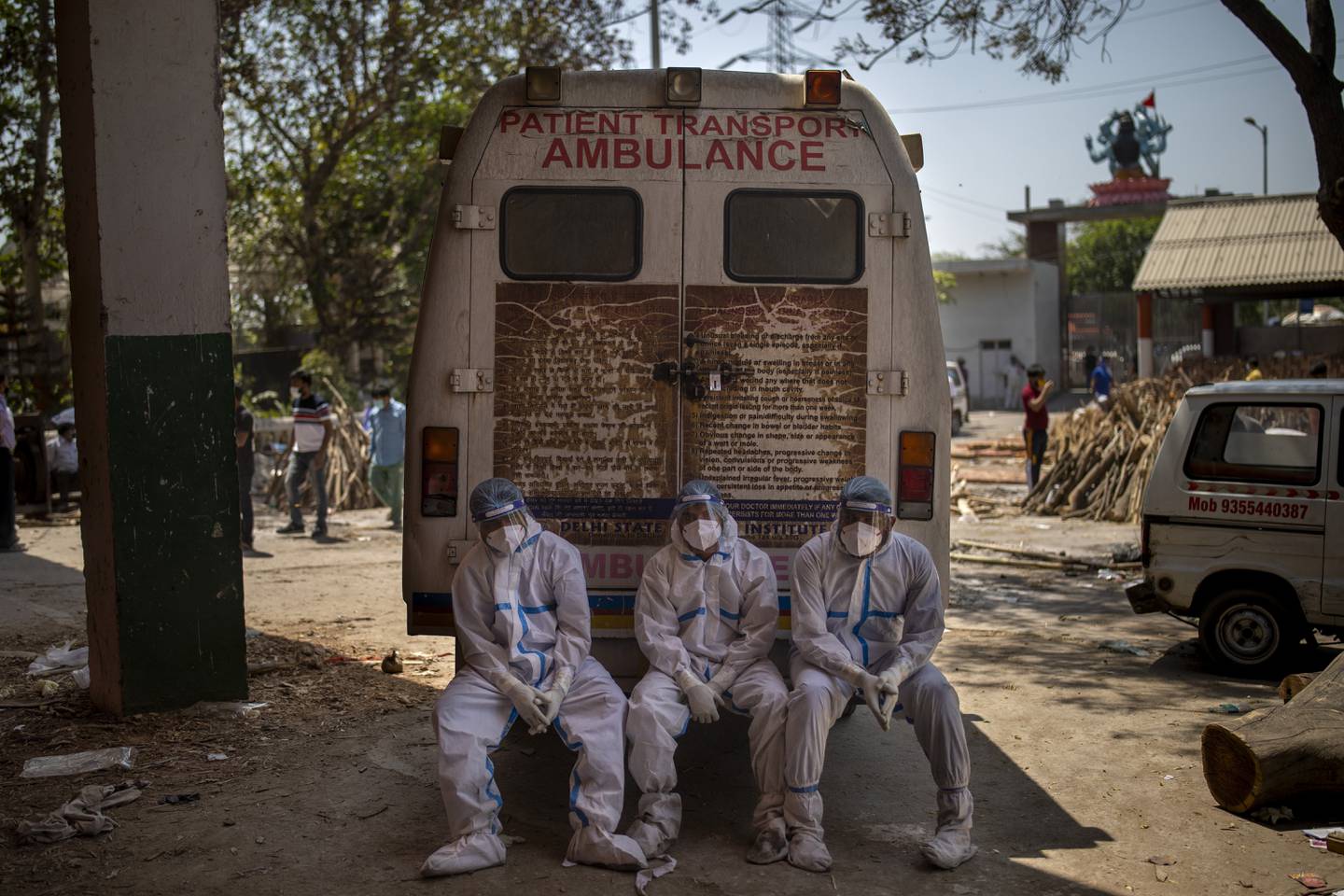 Utslitte arbeidere tar en pause ved et krematorium i New Delhi i India. Foto: Altaf Qadri / AP / NTB