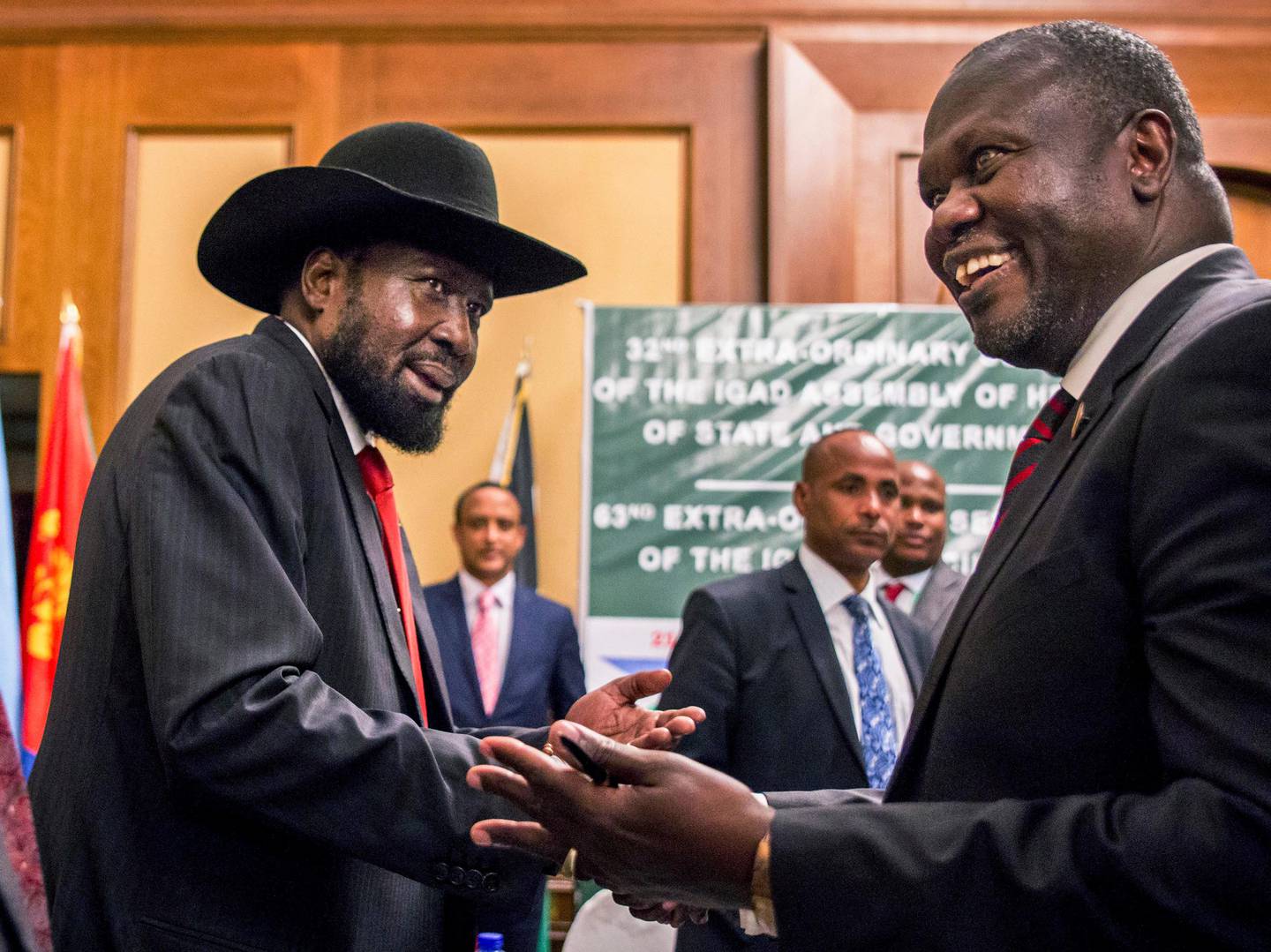 FILE - In this Thursday, June 21, 2018 file photo, South Sudan's President Salva Kiir, left, and opposition leader Riek Machar shake hands during peace talks in Addis Ababa, Ethiopia. South Sudan's committee overseeing the fragile transition from civil war has approved almost $185 million in spending on vehicles, food and home renovations while the country's peace deal suffers from an alleged lack of funds, according to internal documents seen by The Associated Press. (AP Photo/Mulugeta Ayene, File)
