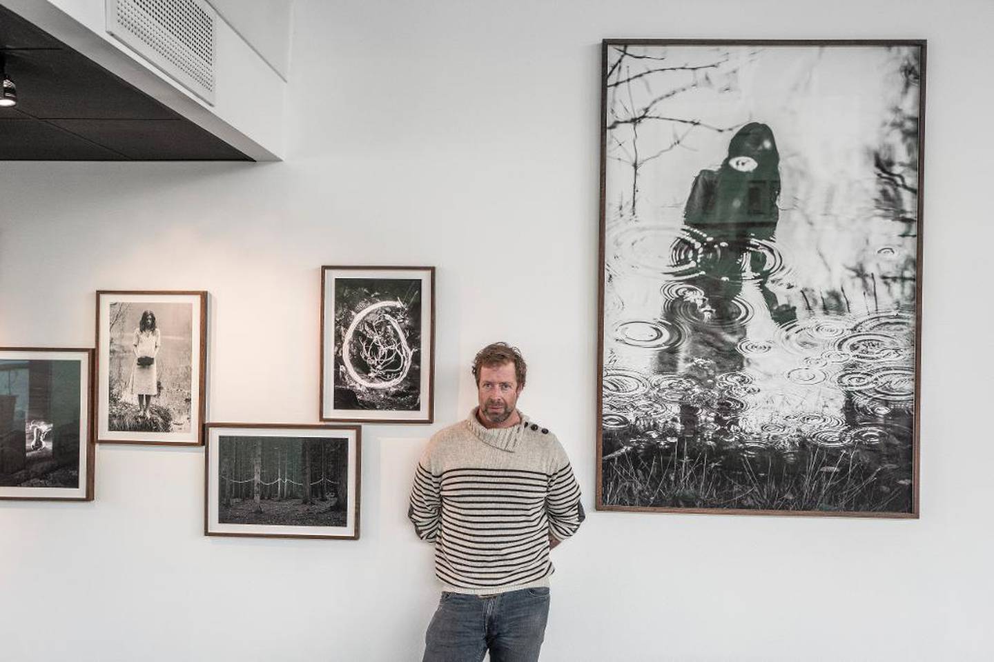 Fotokunstner Christian Houge, foran bilder fra ritual-serien som henger på Maaemo i Oslo.