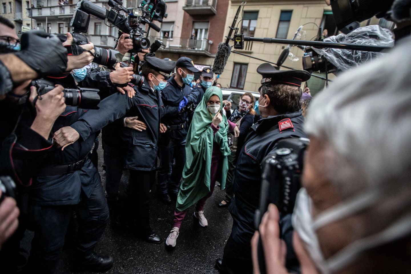 Silvia Romano, escorted by Carabinieri, arrives at her home wearing a surgical mask to guard against COVID-19, in Milan, Italy, Monday, May 11, 2020. The young Italian woman has returned to her homeland after 18 months as a hostage in eastern Africa. (AP Photo/Luca Bruno)