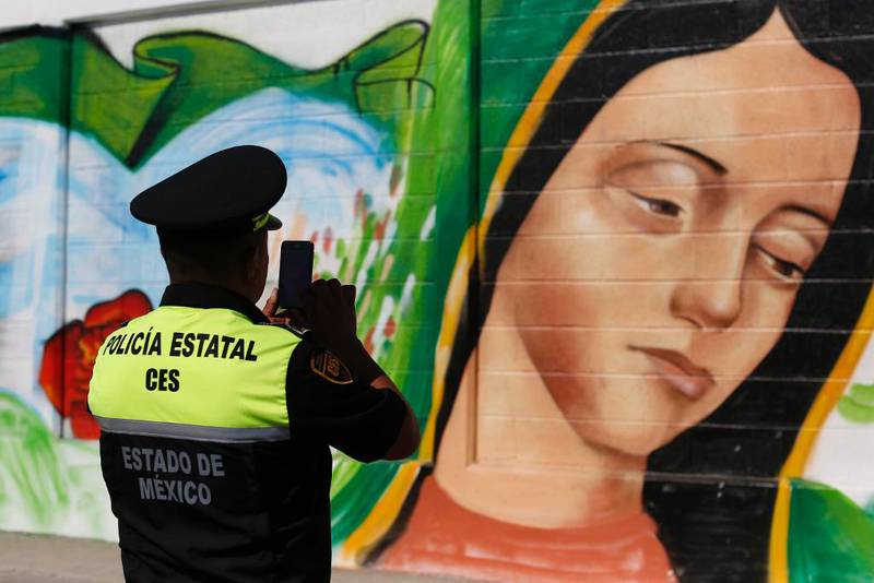 En politimann tar et bilde av et veggmaleri i Mexico City som skal forestille Vår frue av Guadalupe – en av jomfru Marias titler. Foto: AP