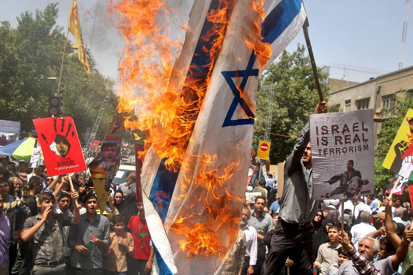 Iranians burn a representation of an Israeli flag as they chant slogans during an annual pro-Palestinian rally marking Al-Quds (Jerusalem) Day in Tehran, Iran, Friday, July 25, 2014. "Al-Quds Day," Arabic for Jerusalem, is the last Friday of the Muslim holy month of Ramadan declared by the Iranian late spiritual leader Ayatollah Ruhollah Khomeini as an international day of struggle against Israel and for the liberation of Jerusalem. Alongside Mecca and Medina in Saudi Arabia, Jerusalem is sacred for Muslims since they believe Islam's Prophet Muhammad began his journey to heaven from there.(AP Photo/Ebrahim Noroozi)
