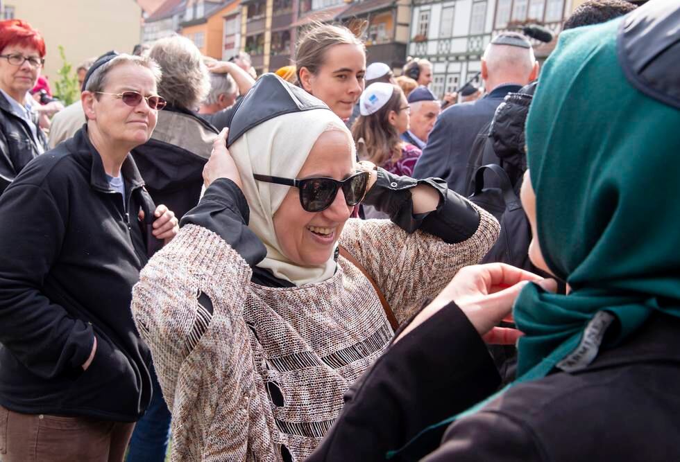 To muslimske kvinner i Erfurt setter på seg det jødiske hodeplagget kippa, tradisjonelt båret av menn, i protest mot at tyske jøder har blitt angrepet på gaten.