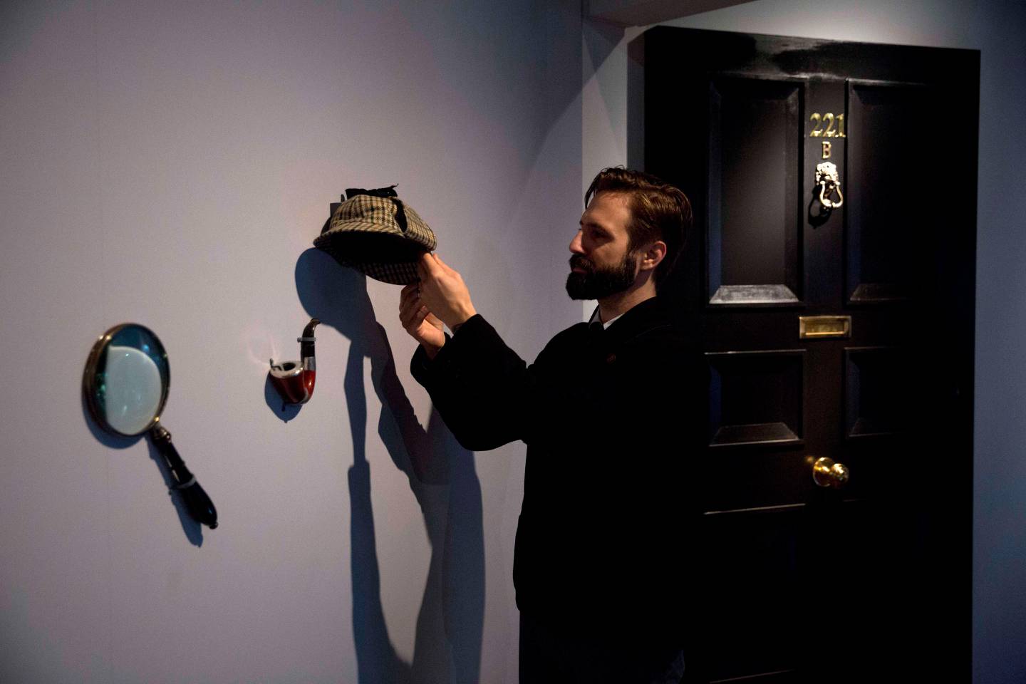 Curator Timothy Long poses for photographers with a Sherlock Holmes style pipe, deerstalker hat, and magnifying glass displayed beside an interpretation model of the fictional front door of his address 221B Baker Street which form part of the exhibition "Sherlock Holmes: The Man Who Never Lived and Will Never Die" at the Museum of London in London, Thursday, Oct. 16, 2014. The exhibition, which opens to the public on Friday, is the largest on the fictional detective created by Scottish author Sir Arthur Conan Doyle to be held in the UK for 60 years.  (AP Photo/Matt Dunham) / TT / kod 436