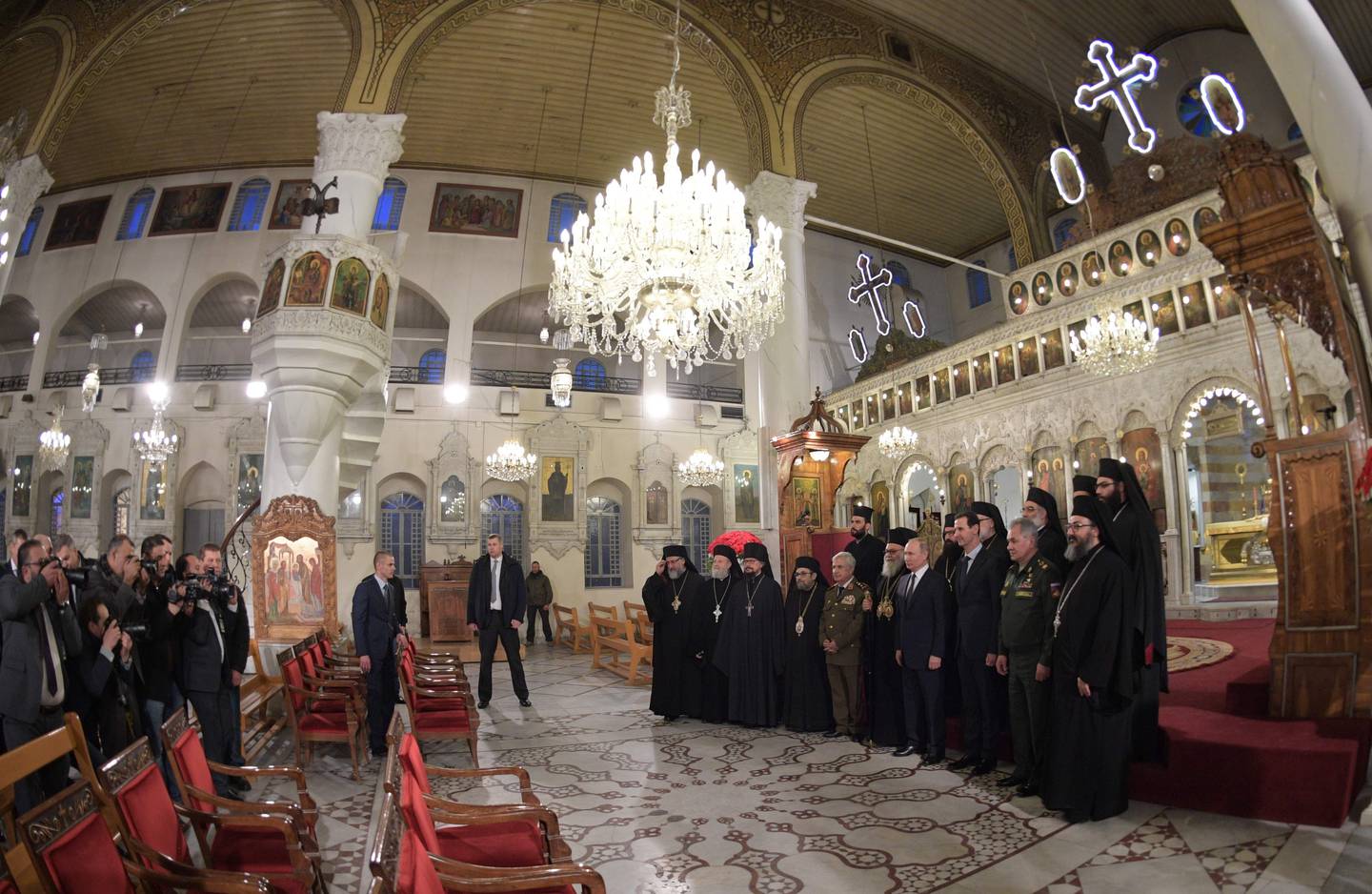 Russian President Vladimir Putin, fourth right in the first row, and Syrian President Bashar Assad, third right in the first row, pose for the media in an orthodox cathedral for Christmas, in Damascus, Syria, Tuesday, Jan. 7, 2020. Putin has traveled to Syria to meet with President Bashar Assad, a key Iranian ally. The rare visit Tuesday comes amid soaring tensions between Iran and the United States following the U.S. drone strike last week that killed a top Iranian general who led forces supporting Assad in Syria's civil war. (Alexei Druzhinin, Sputnik, Kremlin Pool Photo via AP)