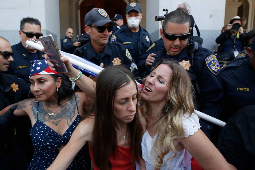 Heidi Munoz Gleisner, left, and Tara Thornton, right, huddle together as they are detained by California Highway Patrol officers during a demonstration against Gov. Gavin Newsom's stay-at-home orders aimed at slowing the spread of the new coronavirus, at the Capitol in Sacramento, Calif., Friday, May 1, 2020. Several people were taken into custody during the protest calling for Newsom to end the restrictions and allow people return to work. (AP Photo/Rich Pedroncelli)