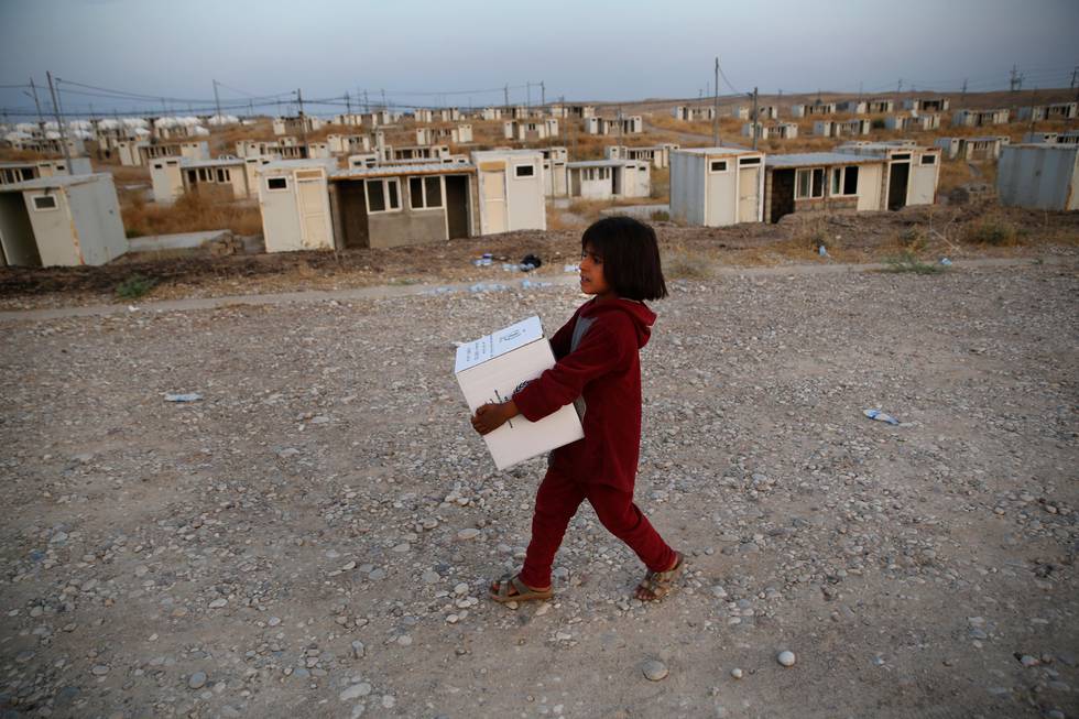 A Syrian girl who was displaced by the Turkish military operation in northeastern Syria, carries a box of food supplies at the Bardarash refugee camp, north of Mosul, Iraq, Thursday, Oct. 17, 2019. Hundreds of refugees have crossed into Iraq in the past week, mostly through unofficial border points. On Wednesday, a first group of 890 people were bused to the Bardarash camp, in northern Iraq's semi-autonomous Kurdish region, which up until two years ago housed displaced people from the Iraqi city of Mosul. (AP Photo/Hussein Malla)