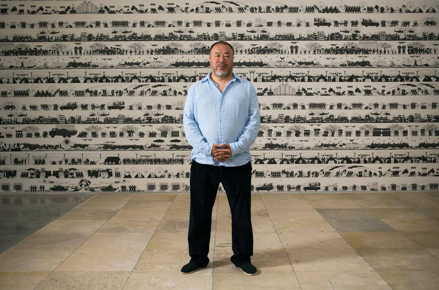 Den kinesiske kunstneren Ai Weiwei foran sitt kunstverk Odyssey –et tapet med relieffer av flyktningers opplevelser av krig, flyktningenes reiser, overfarten over havet, flyktningleirene, demonstrasjoner og protester. Dan Balilty/AP/NTB scanpix 
