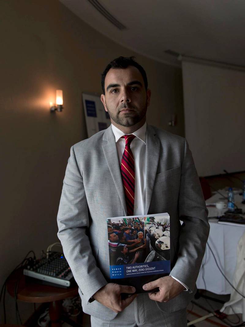 Omar Shakir, Israel and Palestine Director of the New York-based Human Rights Watch, poses with a copy of a report released Tuesday following a two year investigation, in the West Bank city of Ramallah, Tuesday, Oct. 23, 2018. In the report HRW accused Palestinian authorities in the West Bank and Gaza Strip of crushing dissent through routine torture, arbitrary arrest and other tactics. (AP Photo/Nasser Nasser)