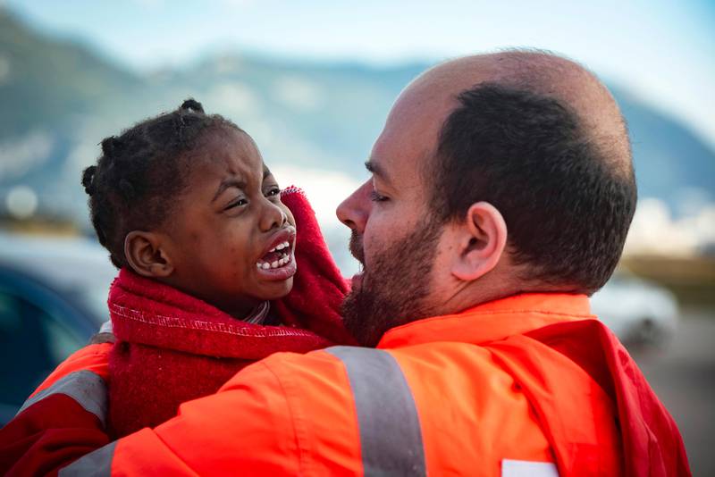 In this photo taken on Saturday, Oct. 27, 2018, a child is carried by a member of Spain's Maritime Rescue Service as they arrive at the port of San Roque, southern Spain, after being rescued by Spain's Maritime Rescue Service in the Strait of Gibraltar. Spain's maritime rescue service saved 520 people trying to cross from Africa to Spain's shores on Saturday. Also, one boat with 70 migrants arrived to the Canary Islands. Over 1,960 people have died trying to cross the Mediterranean to Europe this year, according to the United Nations. (AP Photo/Marcos Moreno)