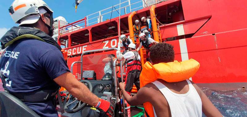 Rescued migrants are helped boarding the Ocean Viking ship, operated by the NGOs Sos Mediterranee and Doctors Without Borders, in the Mediterranean Sea, Tuesday, Aug. 13, 2019. More than 500 rescued migrants are stuck in the Mediterranean on two NGO boats, as Italy and Malta continue to deny them access to their ports. French charity group Doctors Without Borders (MSF) said late Monday in a tweet that it had completed "a critical rescue" of another 105 people onto the Ocean Viking, raising the total number of migrants on board ship to 356. (Hannah Wallace Bowman/MSF/SOS Mediterranee via AP)