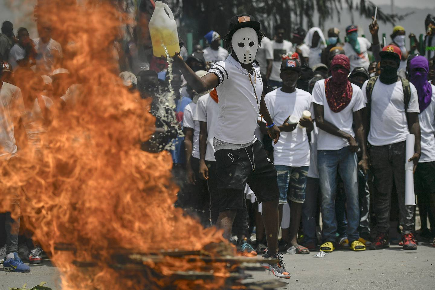 Denne maskerte mannen heller bensin på bålet både i konkret og overført betydning. Han og mange tusen demonstranter tok til gatene i Haiti etter at landets president Jovenel Moise ble skutt og drept i fjor. Demonstrantene krevde at kreftene bak drapet skulle stilles til ansvar.