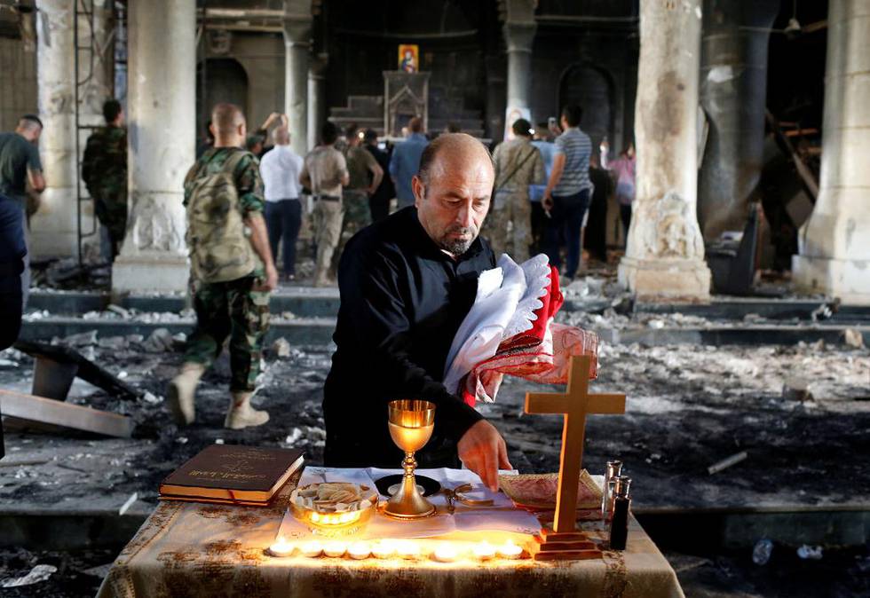 Fire prester deltok i den første gudstjenesten på to år og tre måneder i den kristne byen Qaraqosh i Nord-Irak, etter at ekstremistgruppen IS nå er drevet ut. Her gjør en av de troende gjør forberedelser til søndagens gudstjeneste.