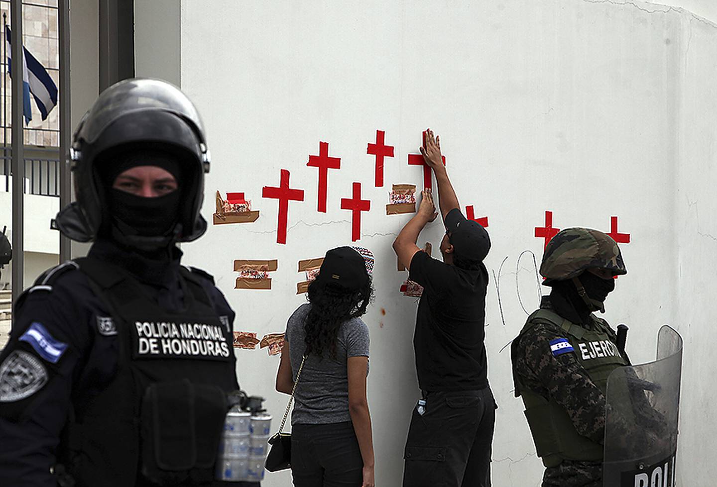 Demonstranter teipet søndag kors på en vegg utenfor sentralbanken i Tegucigalpa, for å markere de mange dødsofrene under de politiske protestene etter presidentvalget.