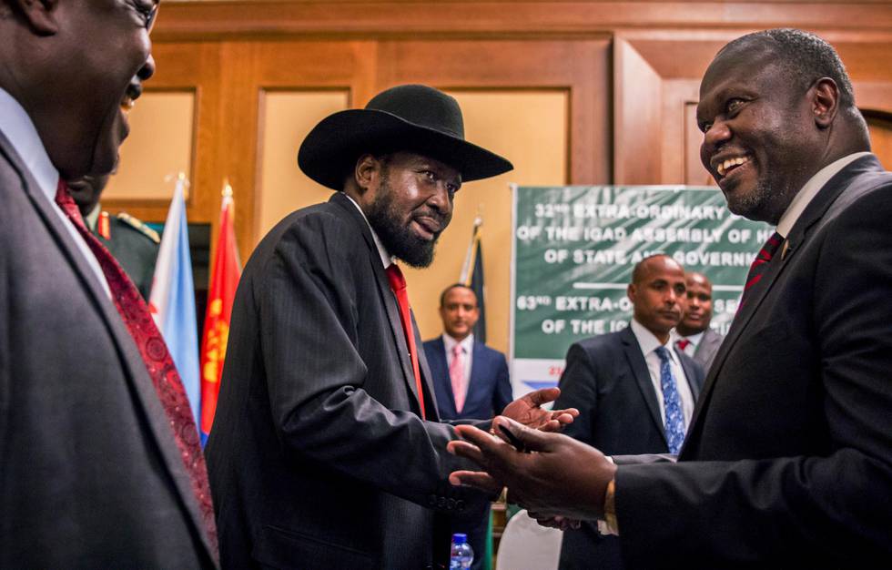 South Sudan's President Salva Kiir, center, and opposition leader Riek Machar, right, shake hands during peace talks at a hotel in Addis Ababa, Ethiopia, Thursday, June 21, 2018. South Sudan's armed opposition on Thursday rejected any "imposition" of a peace deal to end the five-year civil war and asked for more time after the first face-to-face meeting between President Salva Kiir and rival Riek Machar in almost two years. (AP Photo/Mulugeta Ayene)