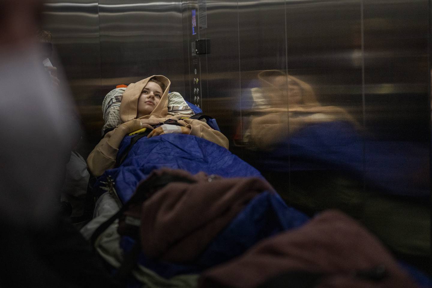 Nastia Kuzik, 21, is carried on a stretcher in a lift while being transported by a medical team to Germany, at a public hospital in Kyiv, Ukraine, Thursday, May 5, 2022. In the morning on March 17, she went to her brother's house in Chernihiv, then on her way back was caught in a bombing. She lost her right leg below the knee and seriously injured her left leg. Has now been transported to Germany for further treatment. (AP Photo/Emilio Morenatti)
