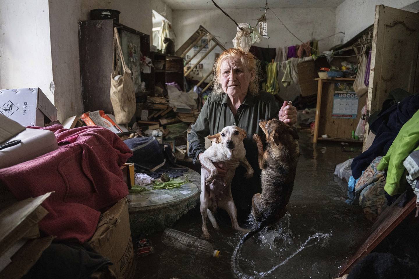 Kherson-innbygger Tetiana holder kjæledyrene sine, Tsatsa og Chunya, mens hun står inne i huset sitt som ble oversvømt etter at Kakhovka-demningen angivelig ble sprengt natt til tirsdag. Foto: Jevhen Maloletka / AP / NTB